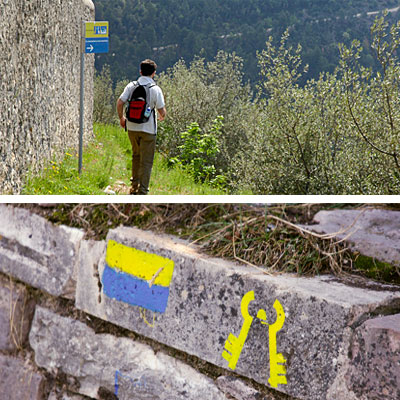 Sinais que indicam a rota do caminho de Francisco de Assis: amarelo-azul e amarelo Tau
